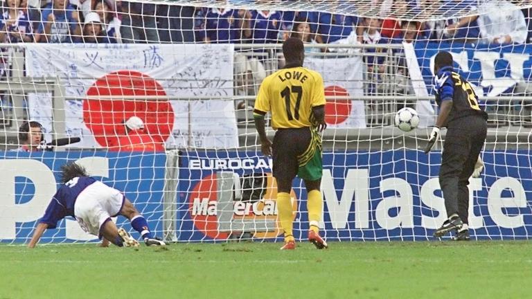 Japanese defender Naoki Soma (L) regains hi balence in front of Jamaican forward Onandi Lowe (C) and Jamaican goalkeeper Aaron Lawrence after a goal by Masashi Nakayama (not in picture) at the Gerland stadium 26 June in Lyon, central France, during the 1998 Soccer World Cup Group H first round third match between Japan and Jamaica. Jamaica beat Japan 2-1 in their first World Cup win. (ELECTRONIC IMAGE) AFP PHOTO (Photo by GERARD MALIE / AFP) (Photo by GERARD MALIE/AFP via Getty Images)
